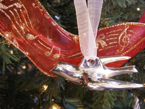 A silver dove ornament with a backdrop of music note garland